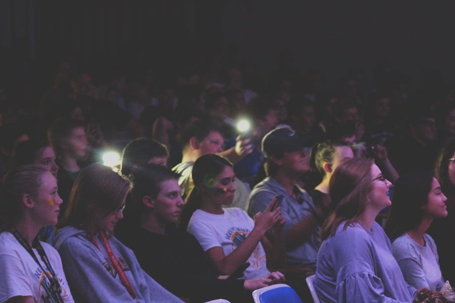 Students wave flashlights while enjoying the performances.