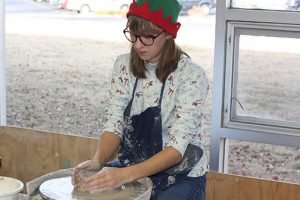 Mary Rongish plays the role of Christmas Elf as she works the pottery wheel. 